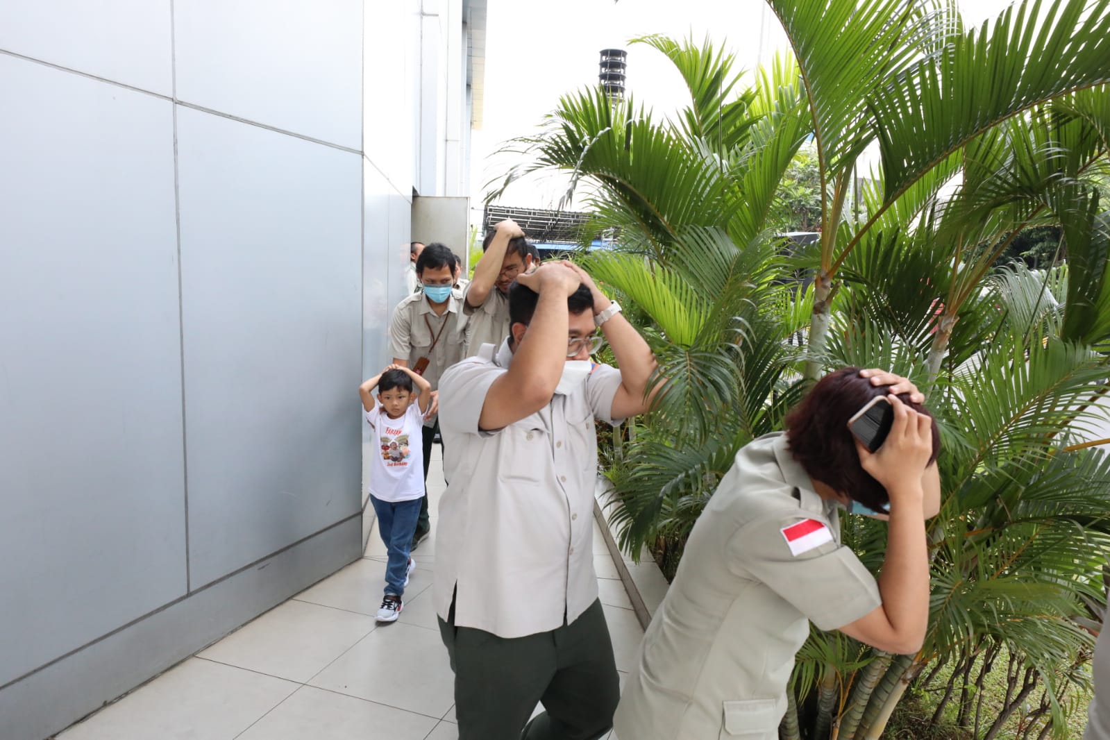 Para pegawai sedang melakukan evakuasi mandiri menuju titik kumpul, saat simulasi evakuasi bencana gempa di Gedung Graha BNPB, Jakarta pada Rabu (26/4).